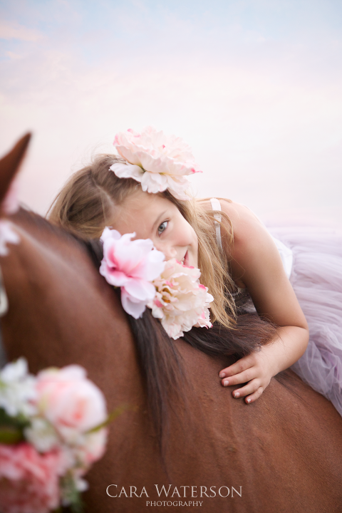 giel peaking past flowers on a horse